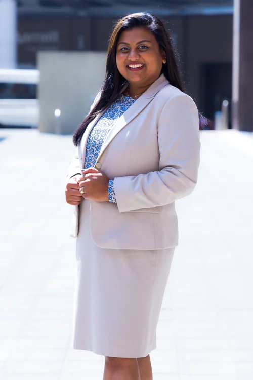 Smiling woman in a cream skirt suit in bright plaza light