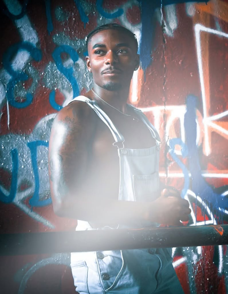 Man in denim overalls against a neon graffiti wall