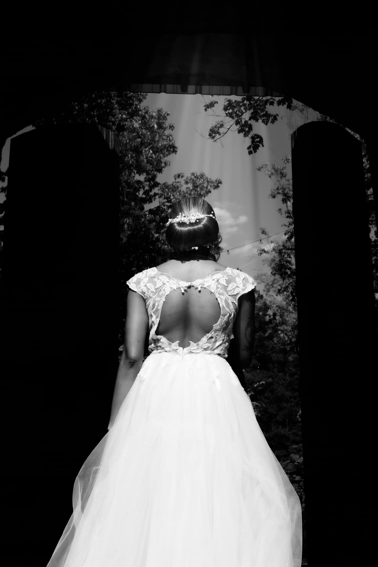 Black and white bride from behind, lace open back, stepping into a garden — Intimate wedding photography by Claudia Quiana