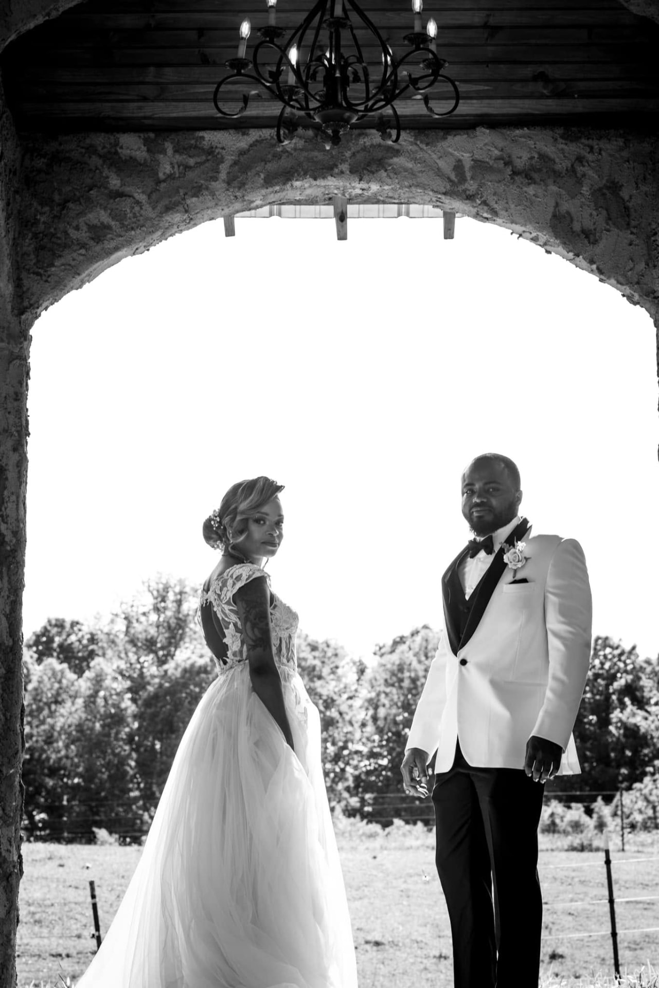 Black and white bride and groom framed by a stone arch