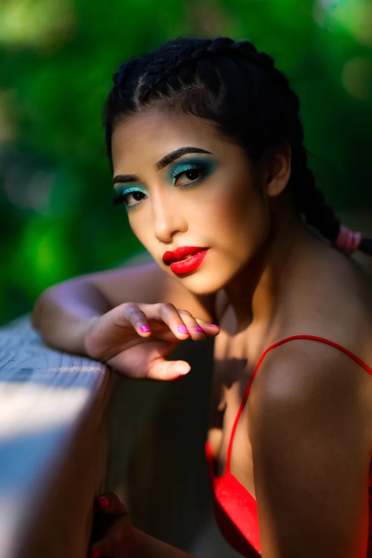Woman with turquoise eyeshadow and red lips resting on the pool edge