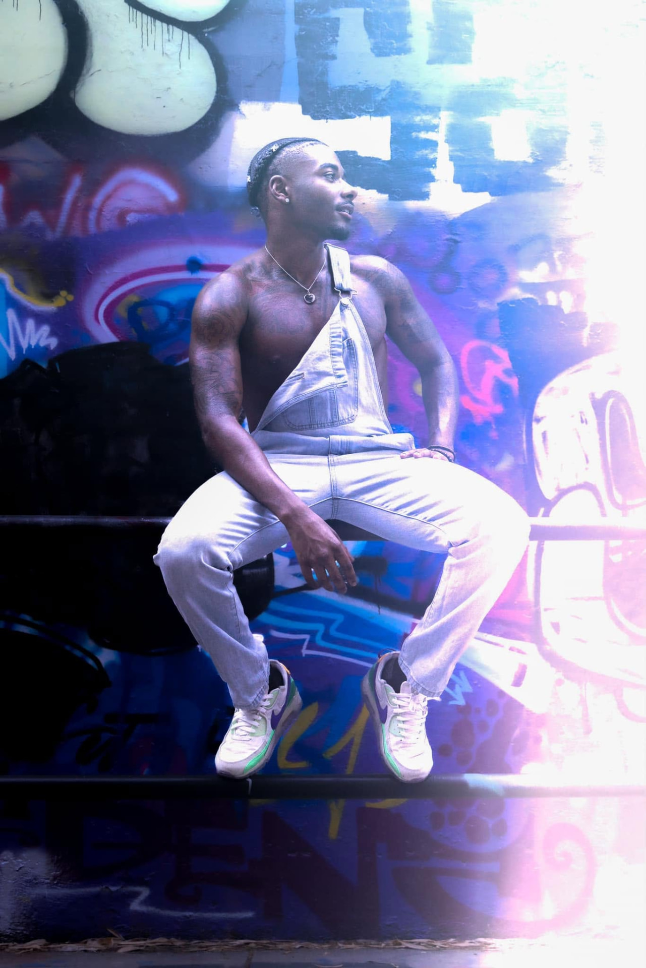 Man in white seated before a vivid graffiti wall
