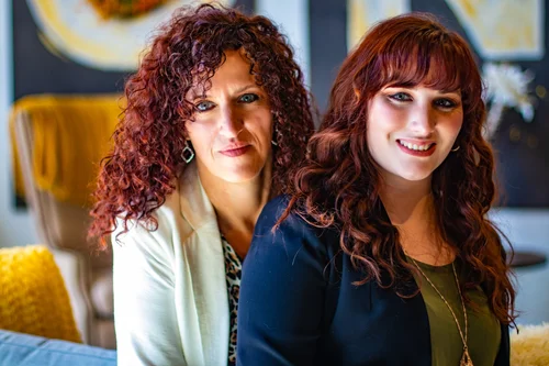 Two women with red curls side by side in a warm lounge