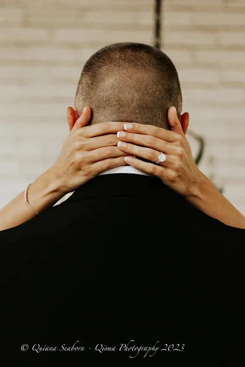 Bride's hands and ring resting on the groom's neck