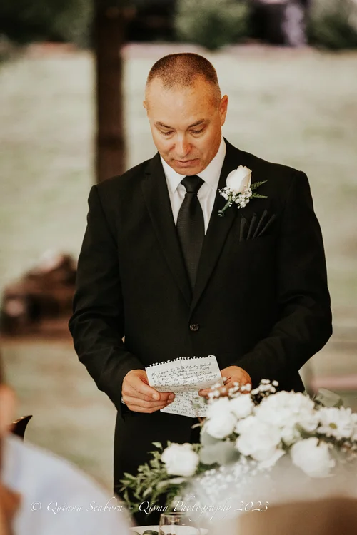 Groom reading his vows beside white flowers