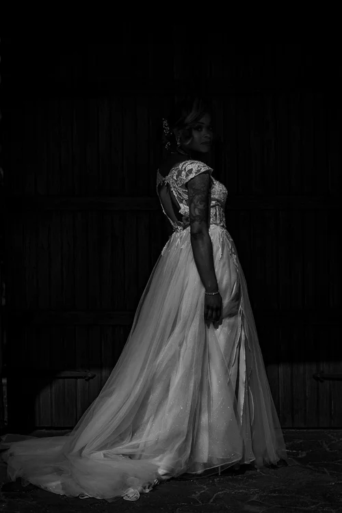 Bride in a lace gown emerging from deep shadow