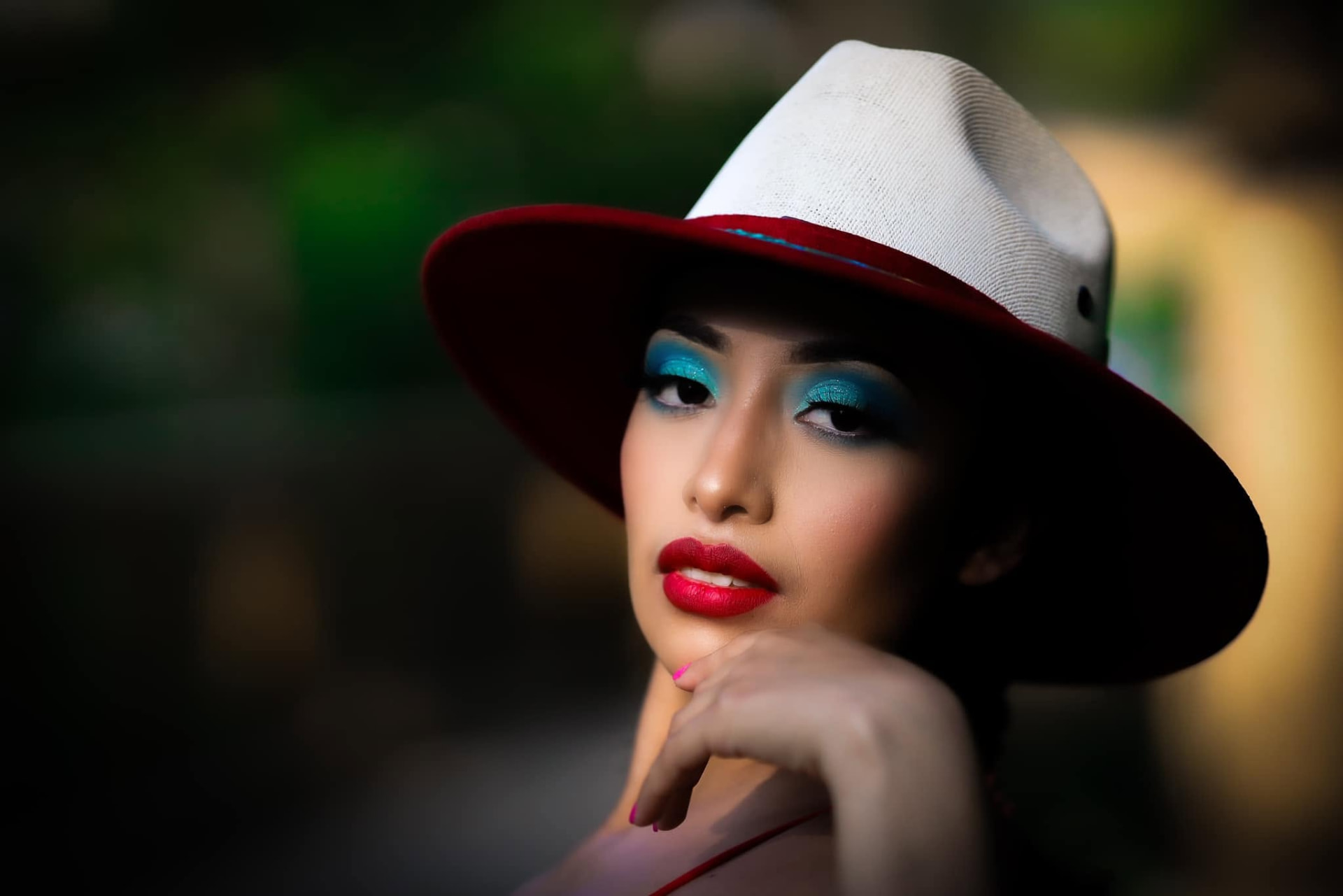 Close portrait in a red-brimmed hat, turquoise eyes and red lips — Editorial lifestyle portrait by Claudia Quiana