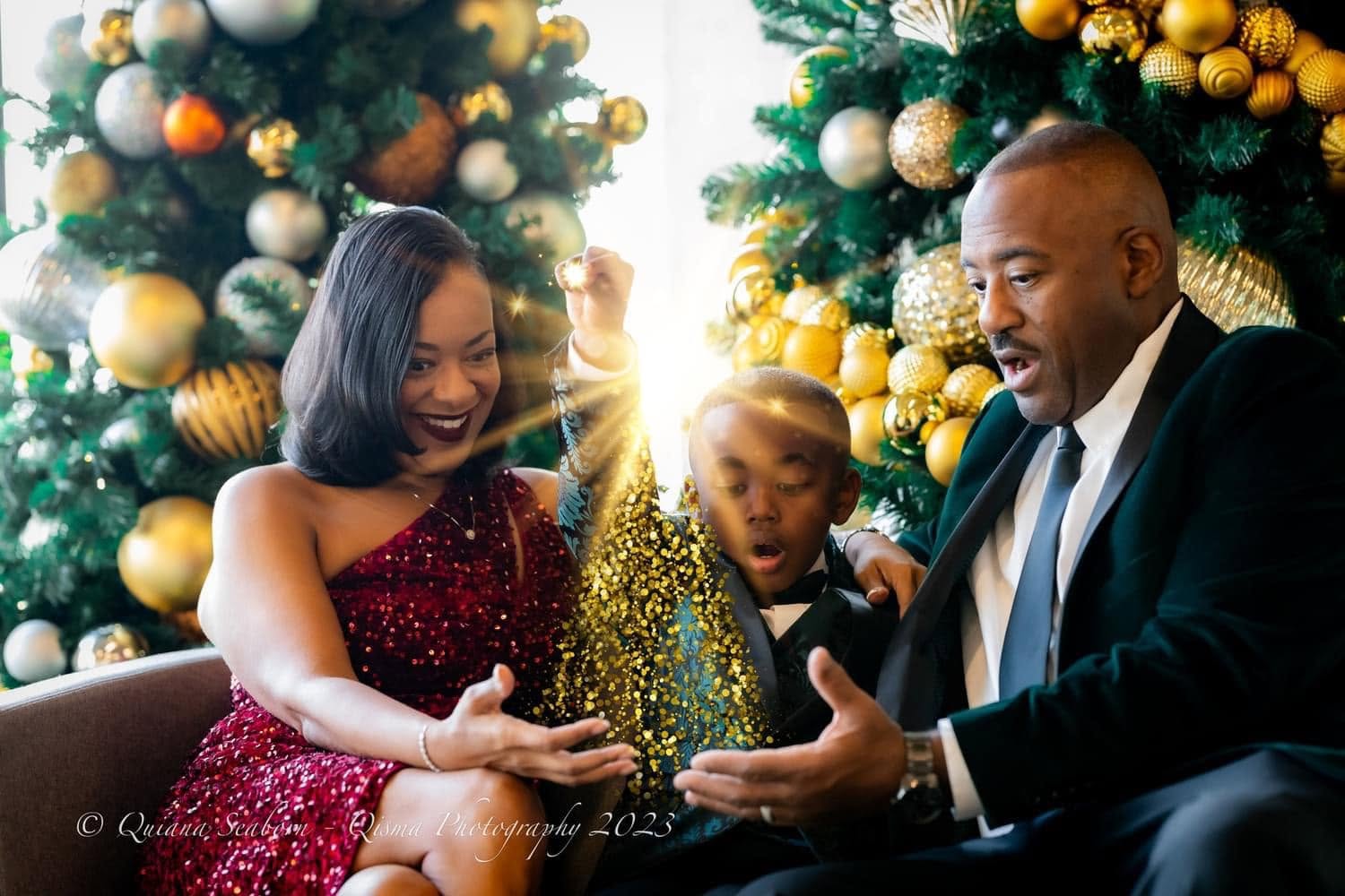 Family sharing a sparkling moment beside a gold Christmas tree