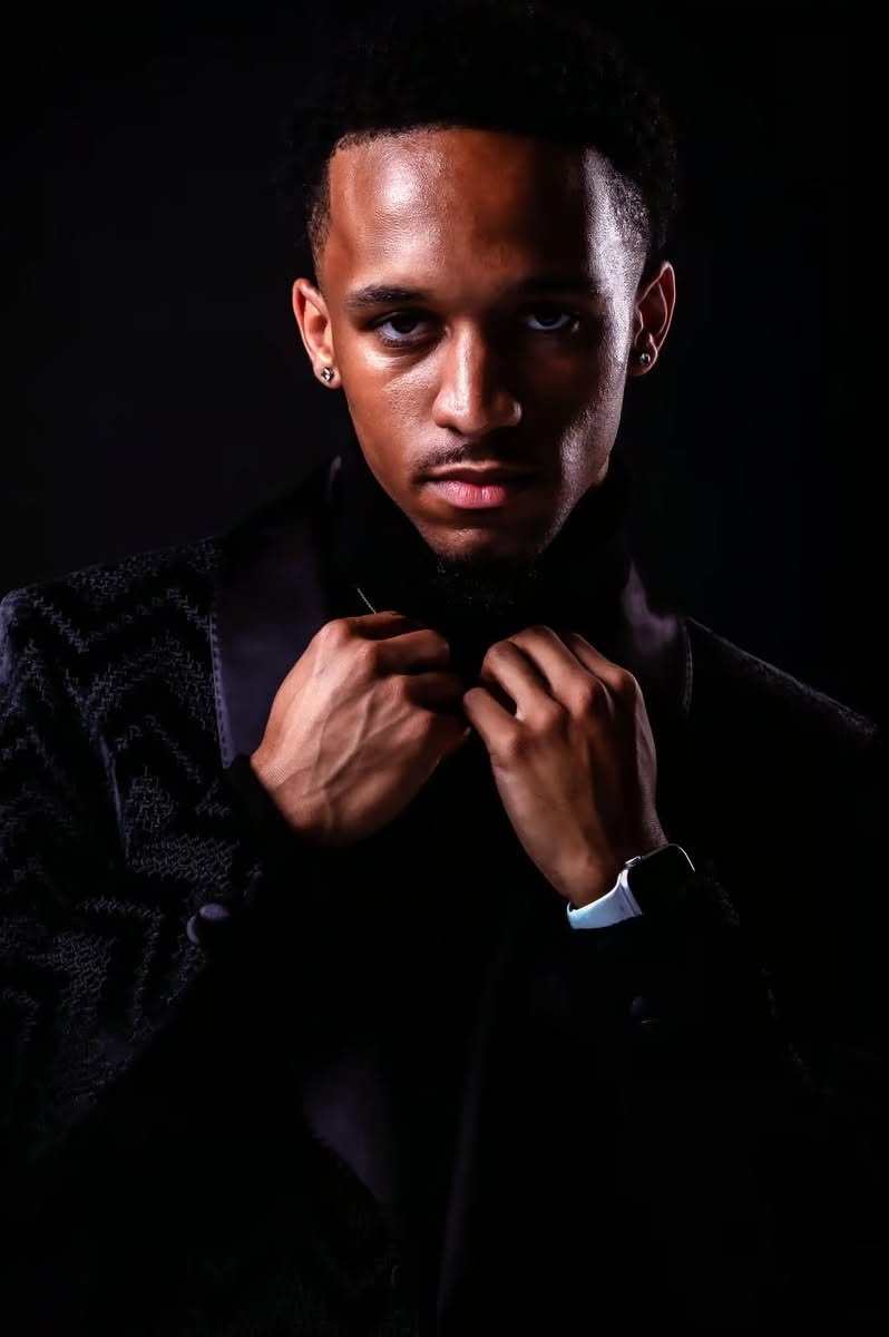 Young man adjusting his collar in low light on black