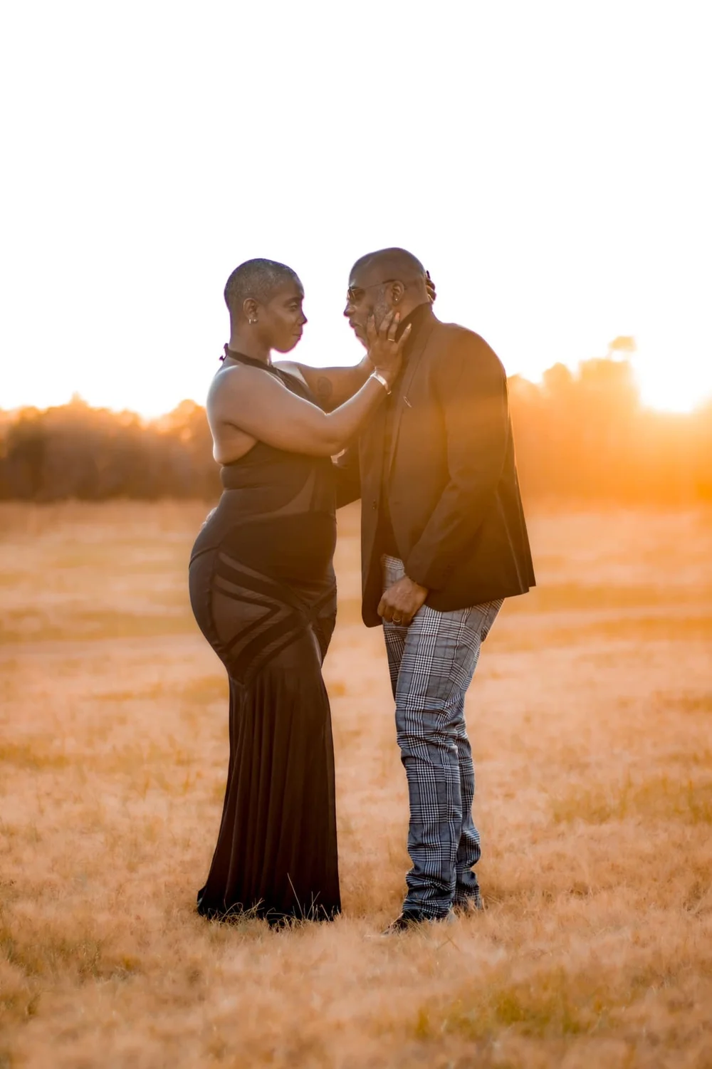 Couple touching faces in a golden field at sunset