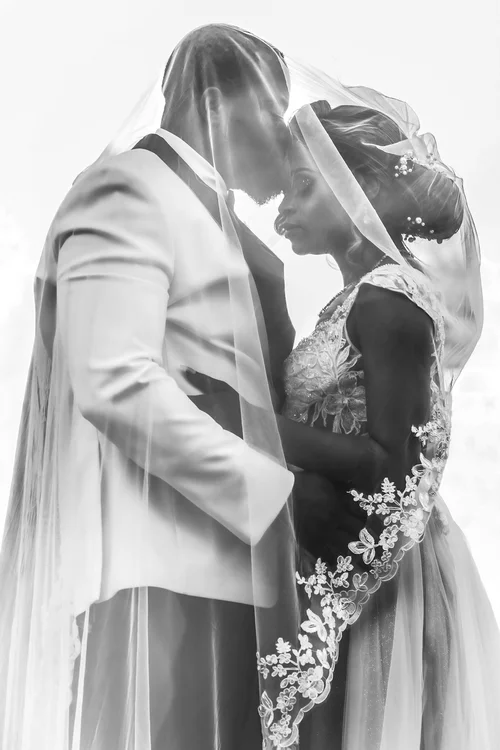 Couple foreheads touching beneath the veil, in soft black and white