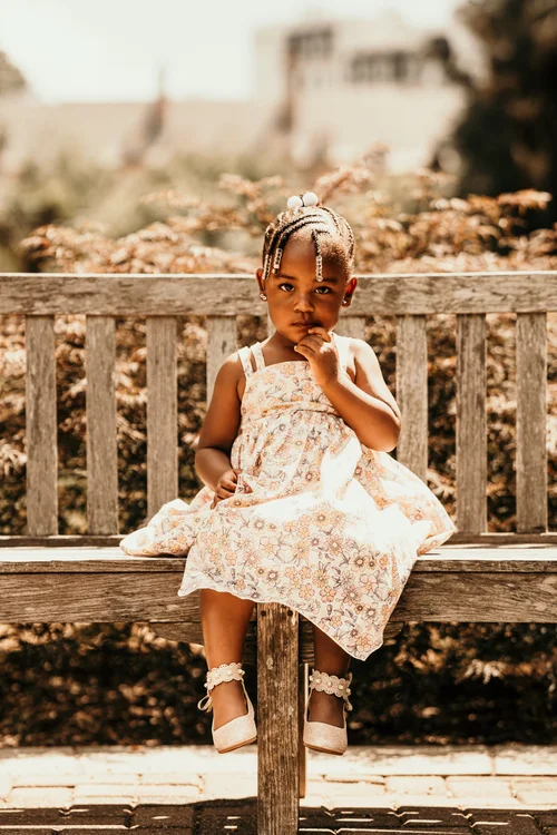 Little girl in a floral dress on a garden bench