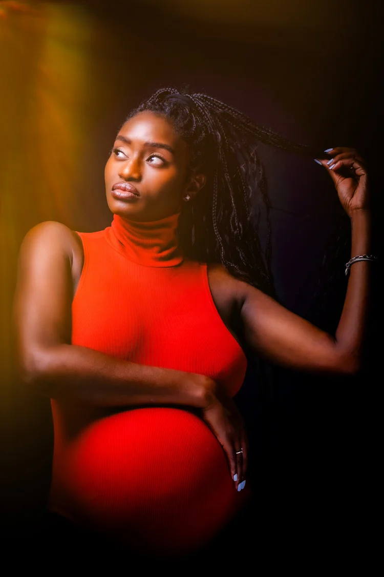 Mother-to-be in red sculpted by warm studio light