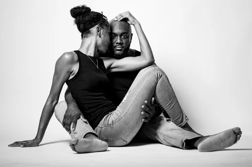Black and white couple seated together on a white studio floor