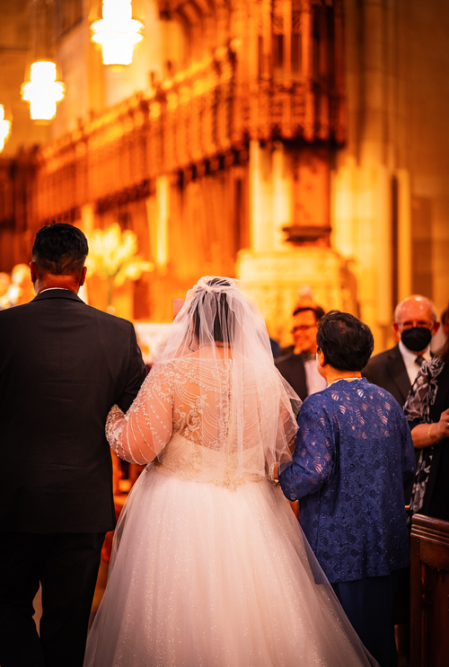 Bride walking down a glowing cathedral aisle with her family — Intimate wedding photography by Claudia Quiana
