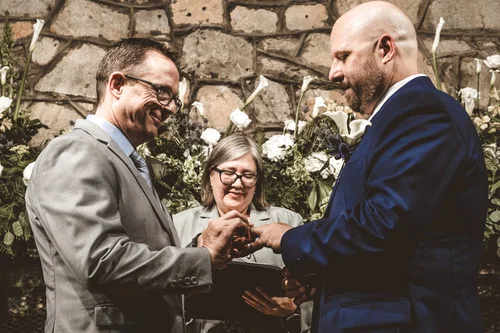 Two grooms laughing through their ring exchange