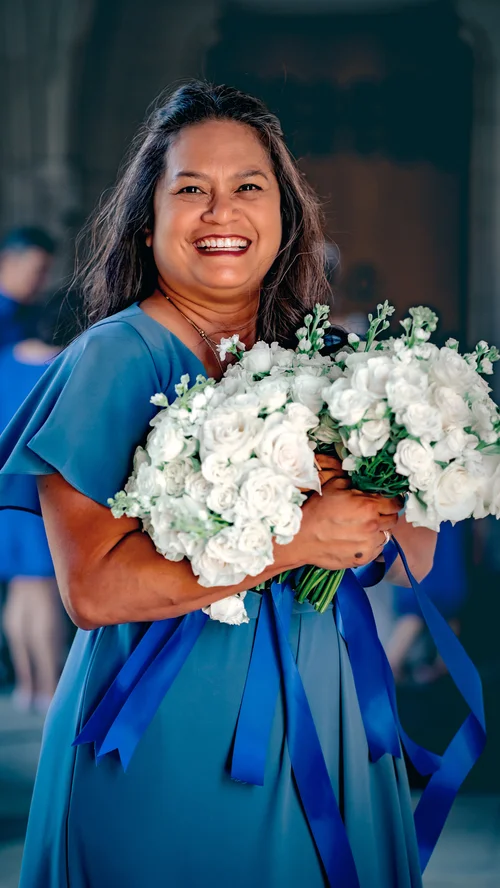 Smiling bridesmaid in blue holding white roses