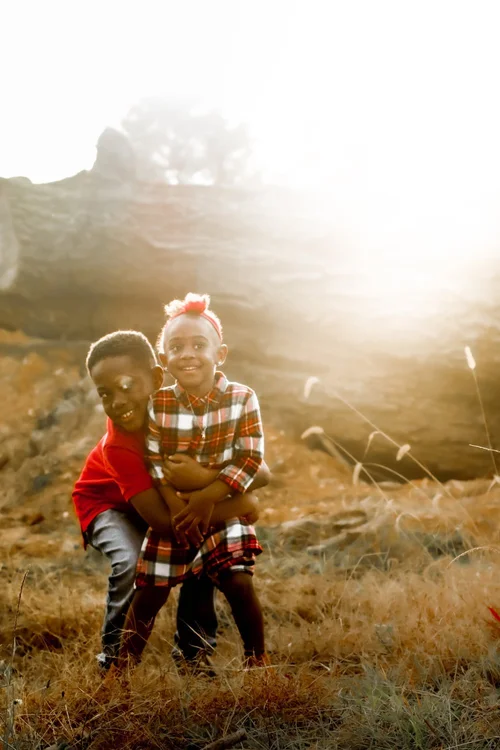 Brother and sister hugging in a burst of sunlight