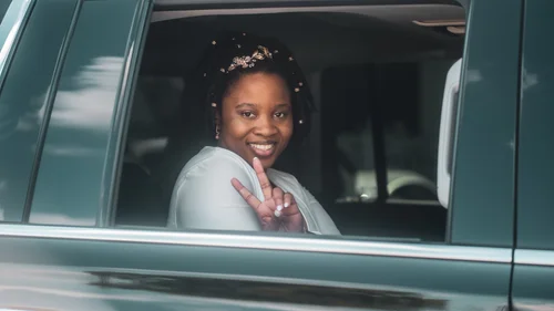 Bride flashing a peace sign from the car window