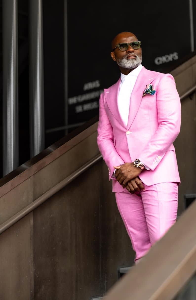 Man in a pink suit leaning on a stair rail