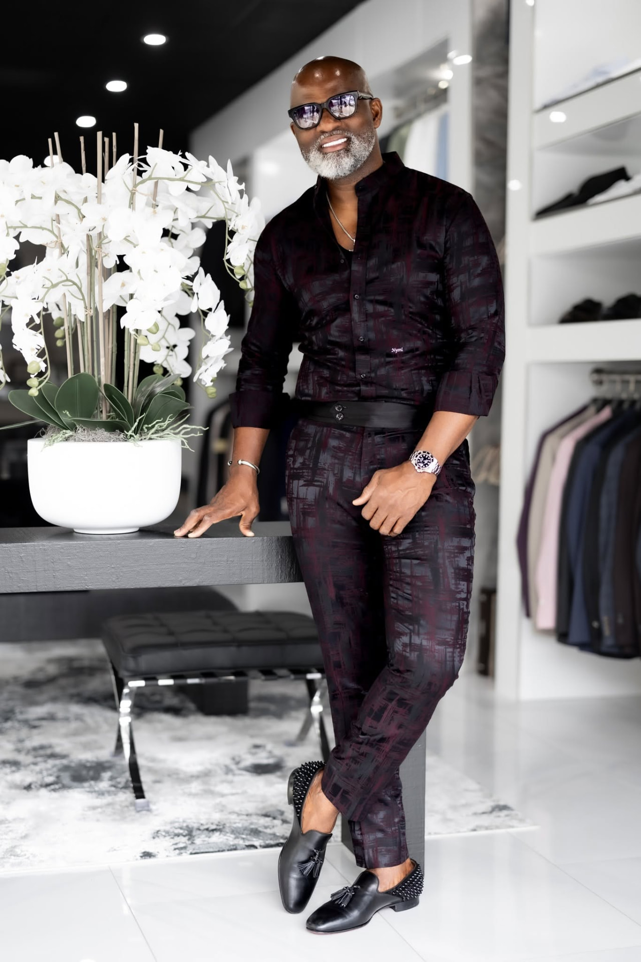 Designer leaning beside white orchids in his showroom