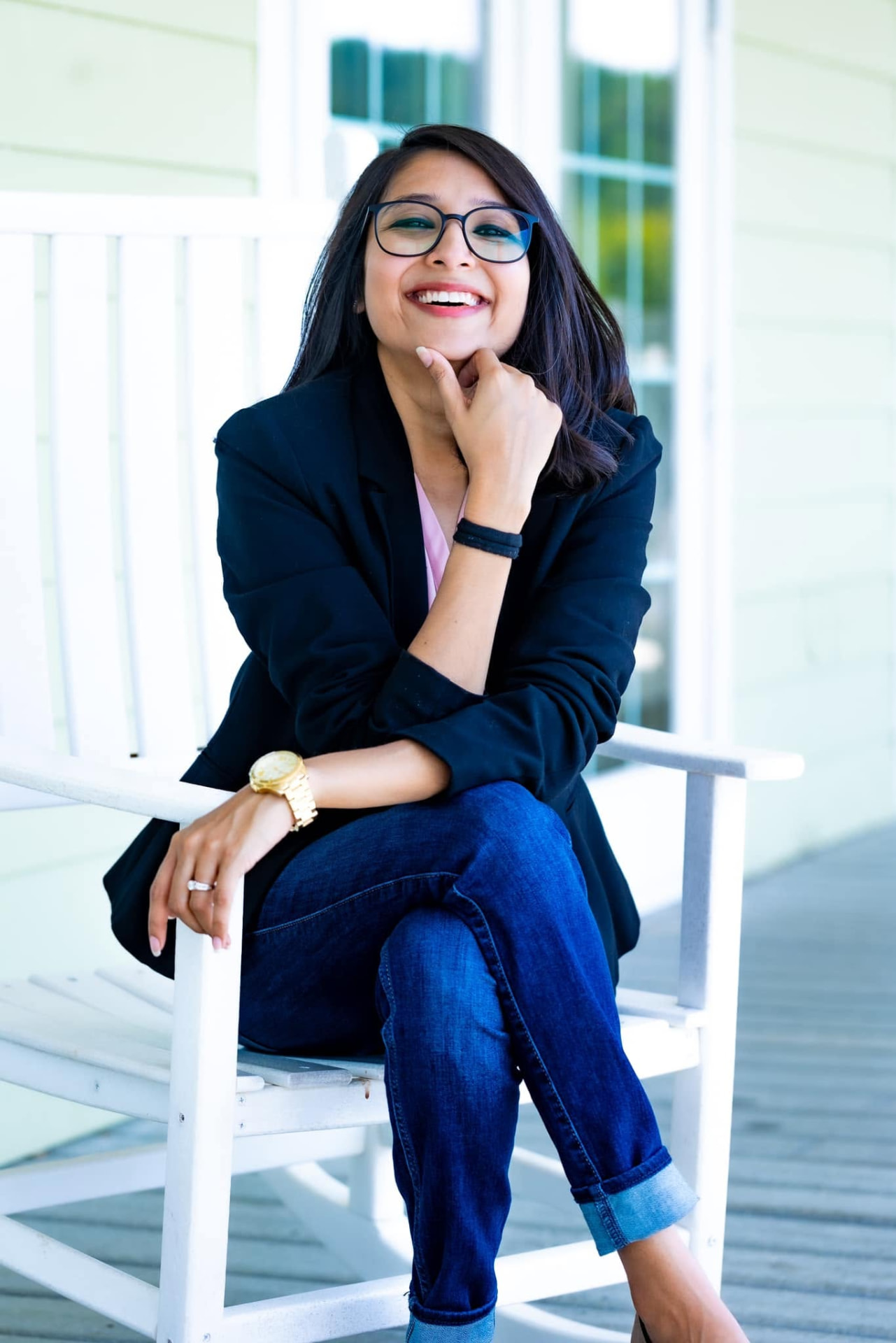 Smiling woman in glasses and a navy blazer on a white porch