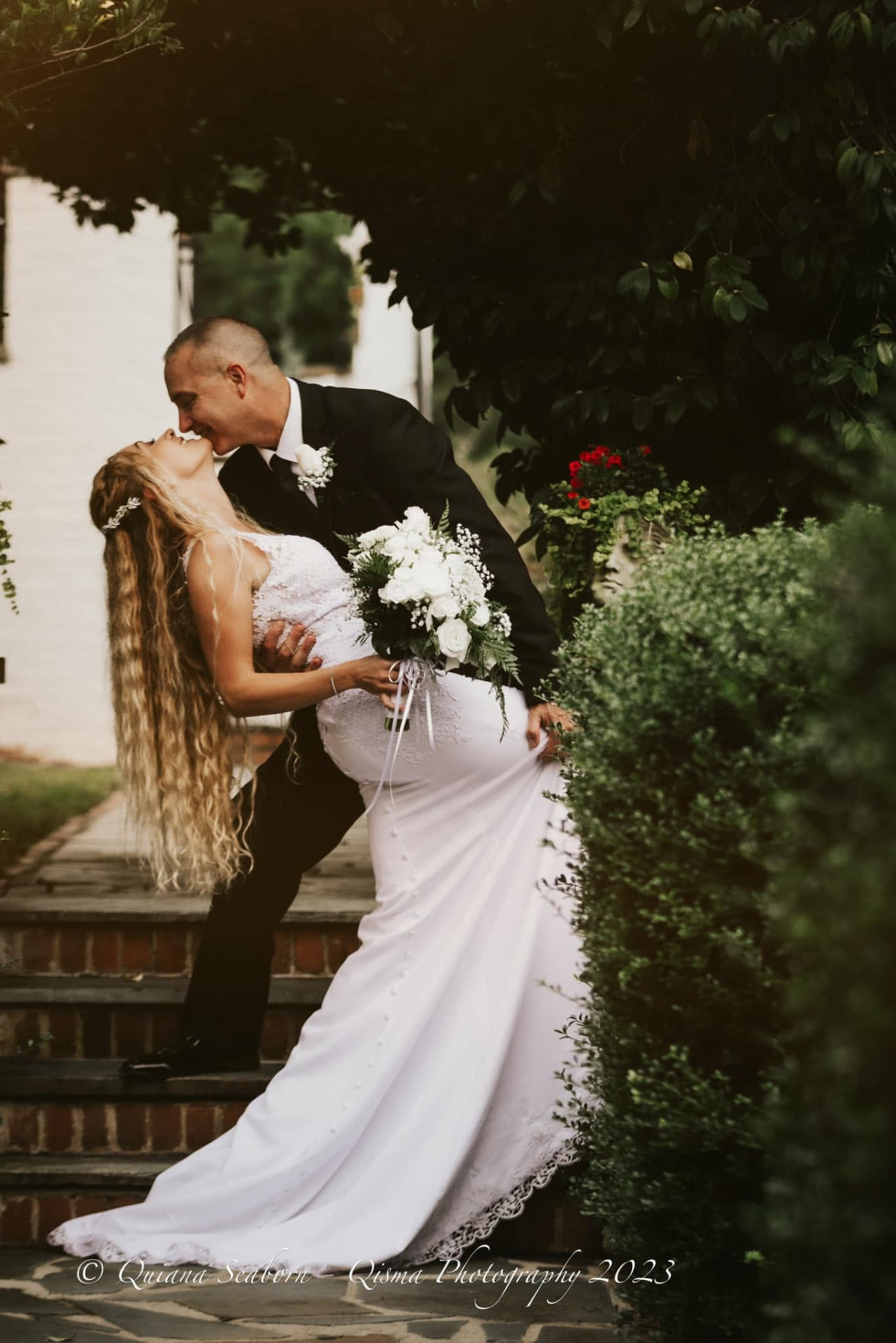 Groom dipping his bride into a kiss on garden steps