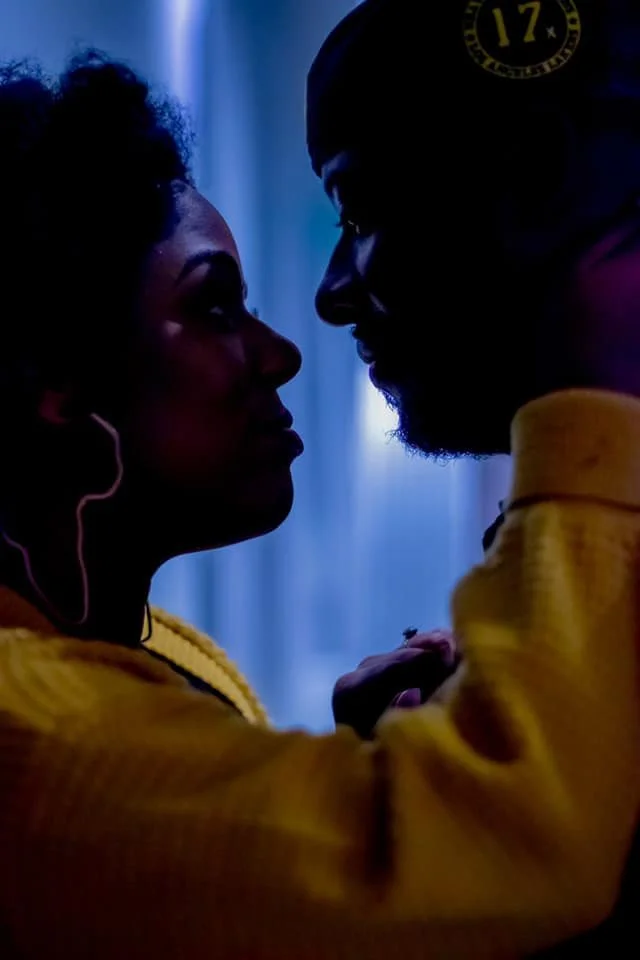 Couple face to face in silhouette against cool blue light