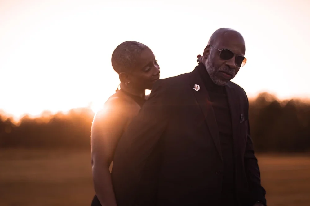 Couple close together, backlit by the setting sun