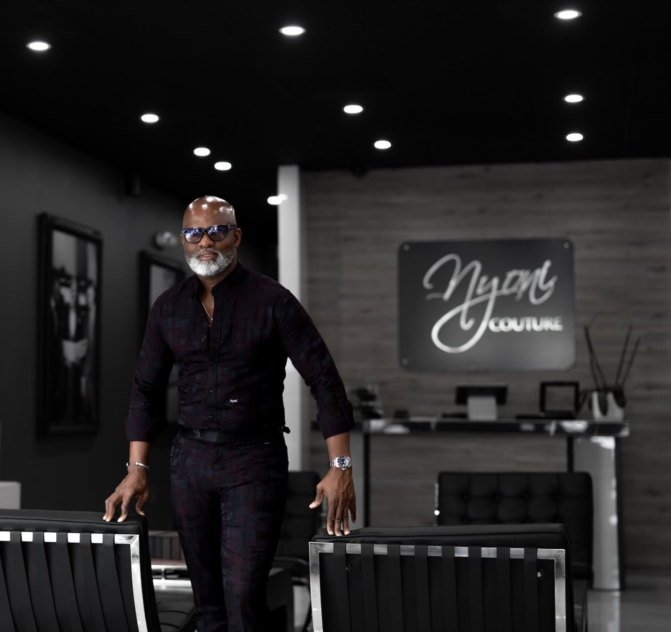 Designer standing among black leather chairs in his couture showroom