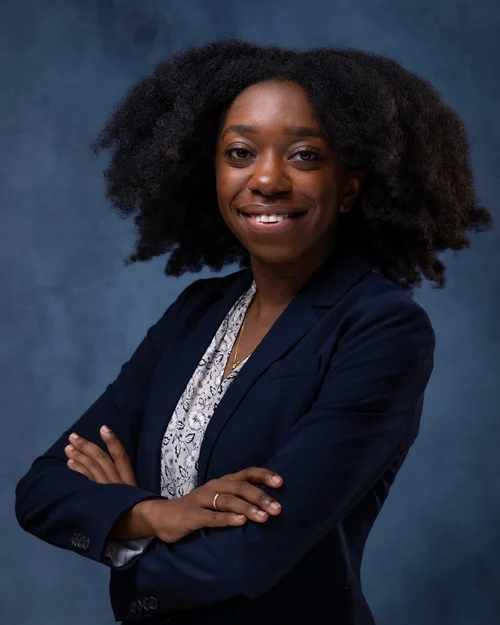 Woman with natural curls in a navy blazer on a blue backdrop