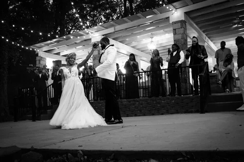 Black and white first-dance twirl under string lights