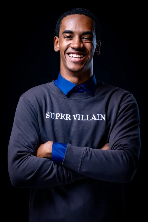 Young man laughing in a Super Villain sweater on black